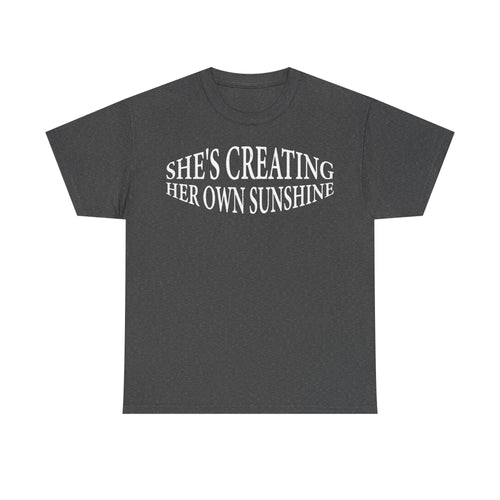 T-shirt with curved white typography reading SHE'S CREATING HER OWN SUNSHINE on charcoal gray fabric.