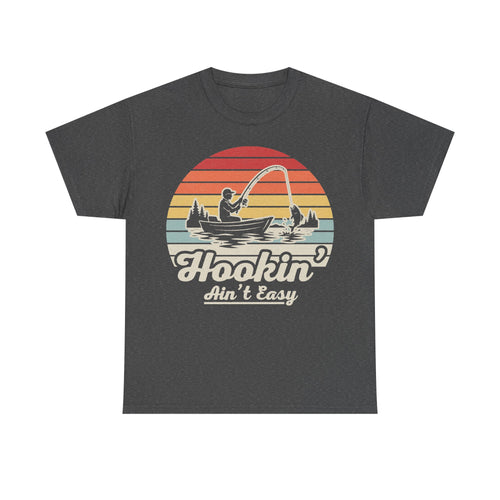 T-shirt with charcoal gray fabric and retro sunset fishing graphic featuring a fisherman in a boat and the text Hookin' Ain't Easy.