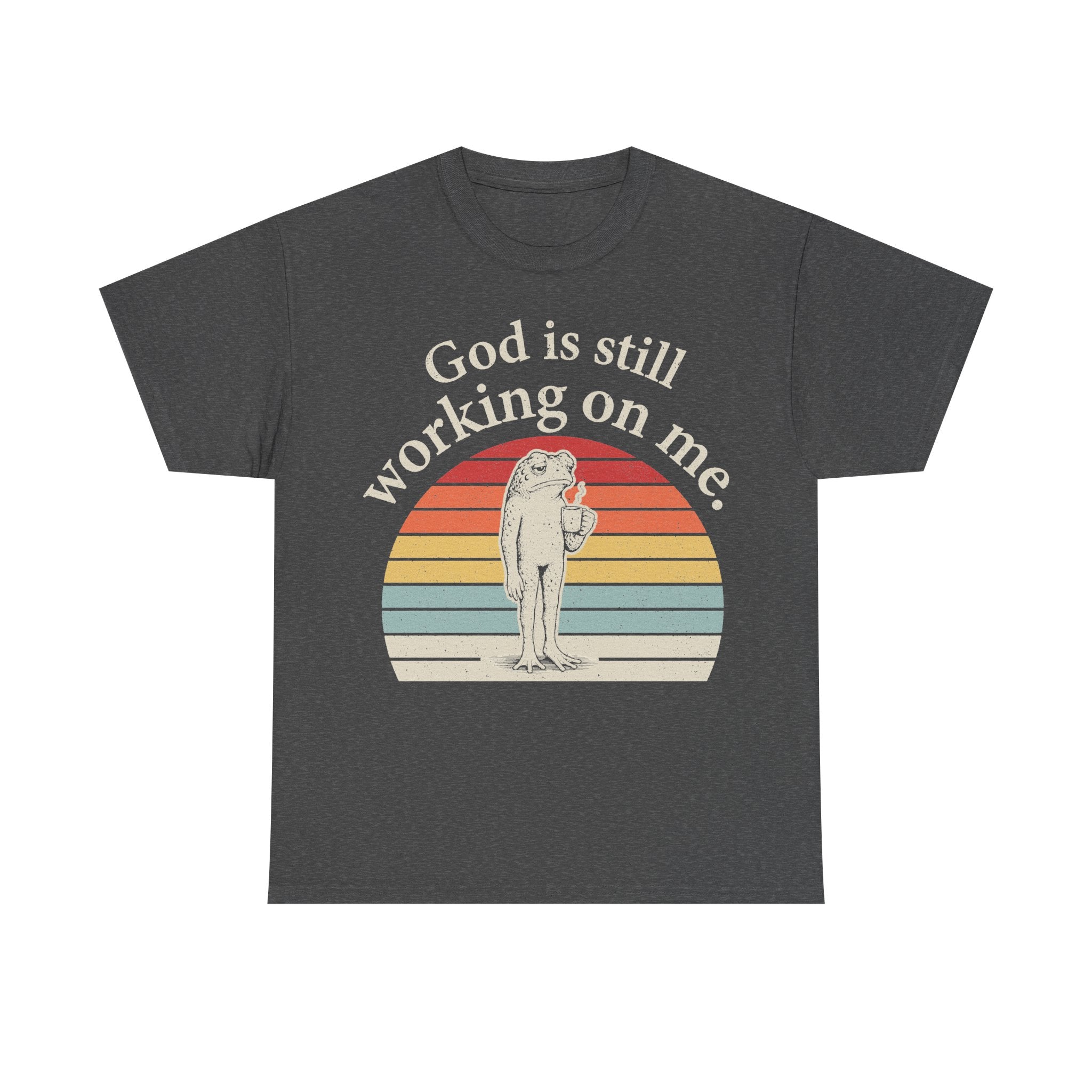 T-shirt in dark charcoal with vintage sunset circle and frog graphic; God is still working on me.