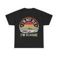 Black T-shirt with a vintage circular sunset car graphic and bold retro typography reading I'M NOT OLD, I'M CLASSIC.